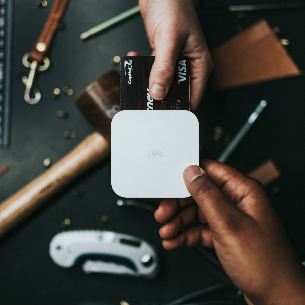 A customer taps a credit card on a portable payment terminal held by a merchant â€” the everyday moment AppKatz apps are built around.